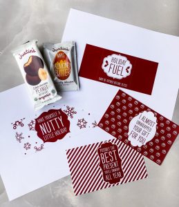 Holiday design sleeves printed on white paper laid out with Justin's products on a textured tabletop
