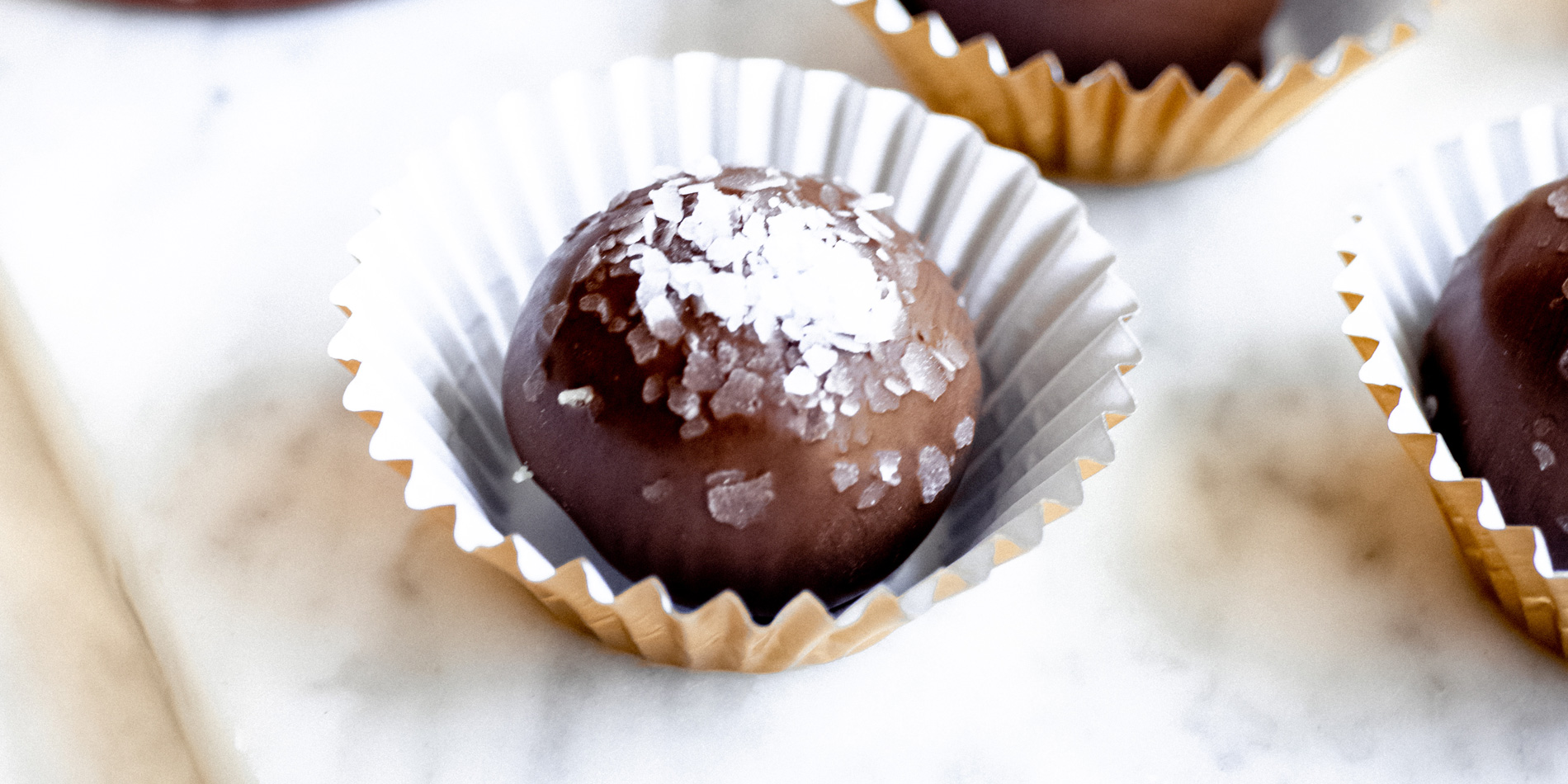 Dark Chocolate Hazelnut and Coconut Truffles in cupcake wrappers on a marble tray on a white background bird's eye view