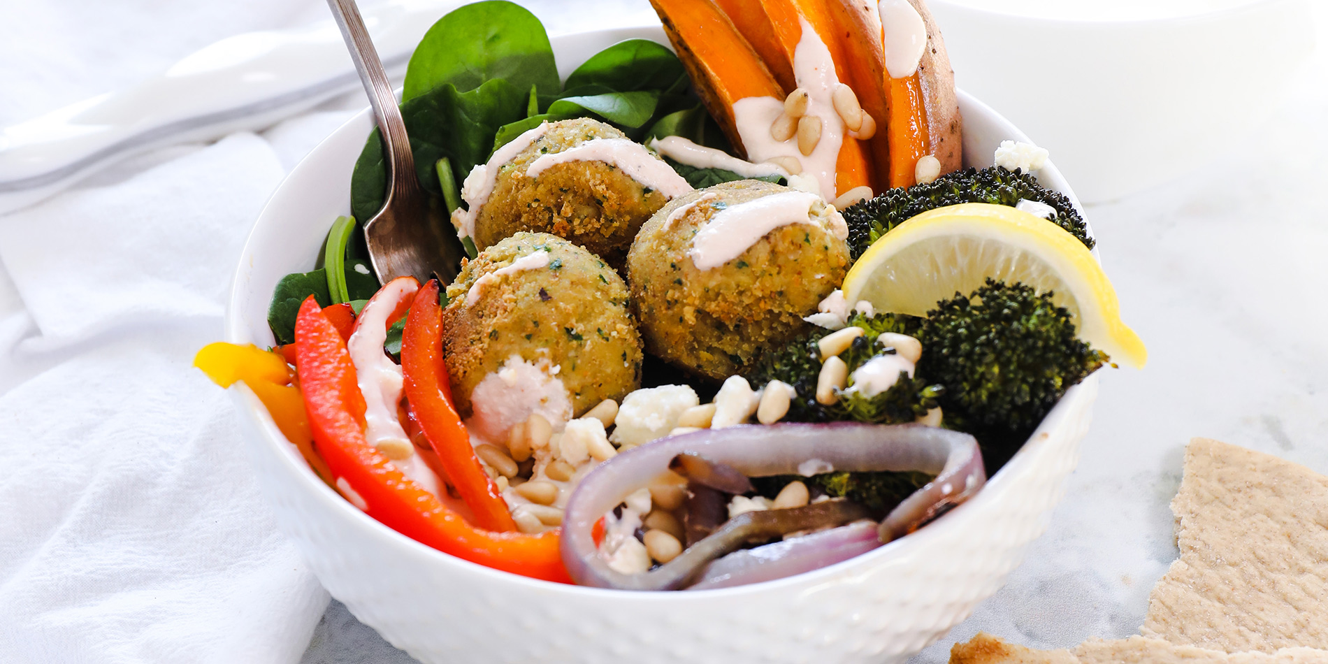 Nutty Falafel sitting in bed of vegetables in a white bowl