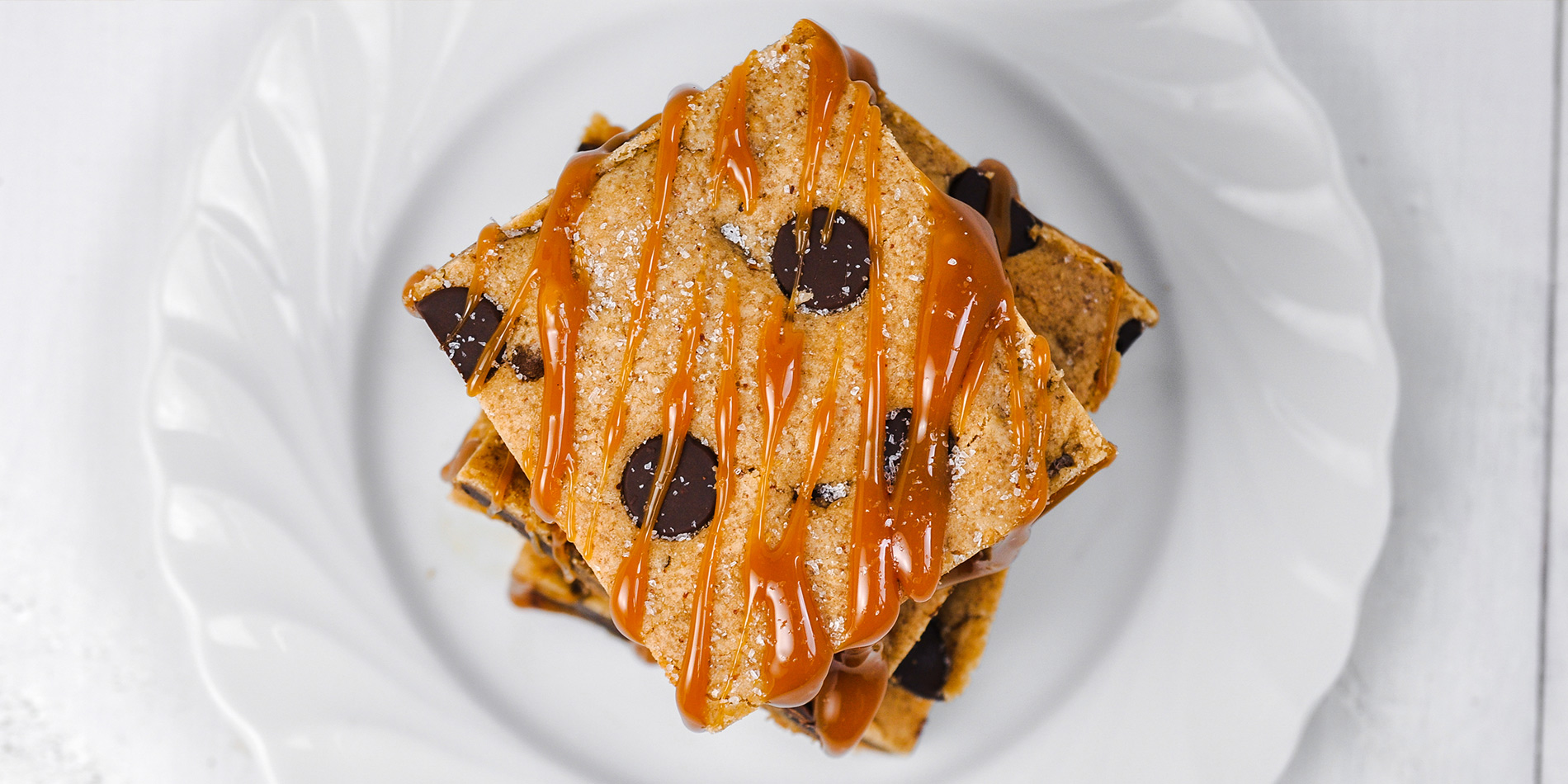 Salted Caramel Chocolate Chip Maple Almond Bars with caramel drizzle on a white plate (bird's eye view) in white background