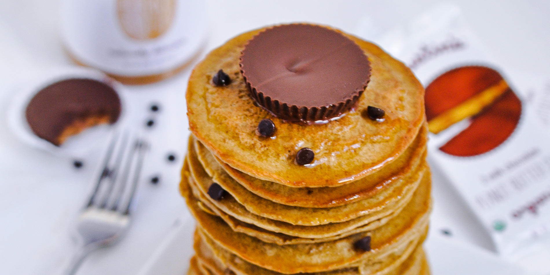 Peanut Butter and Chocolate Chip Protein Pancakes stacked on top with peanut butter cup and chocolate chip sprinkles