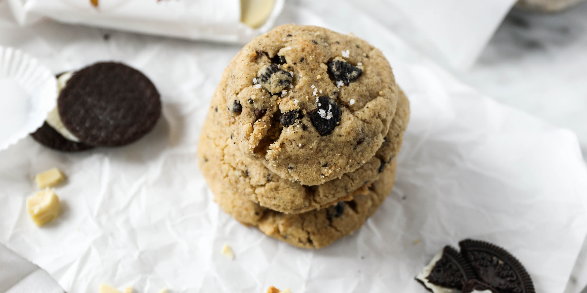 Gluten Free White Chocolate Peanut Butter 'Cookies and Cream' Cookies on parchment with oreo and peanut butter cup chunks