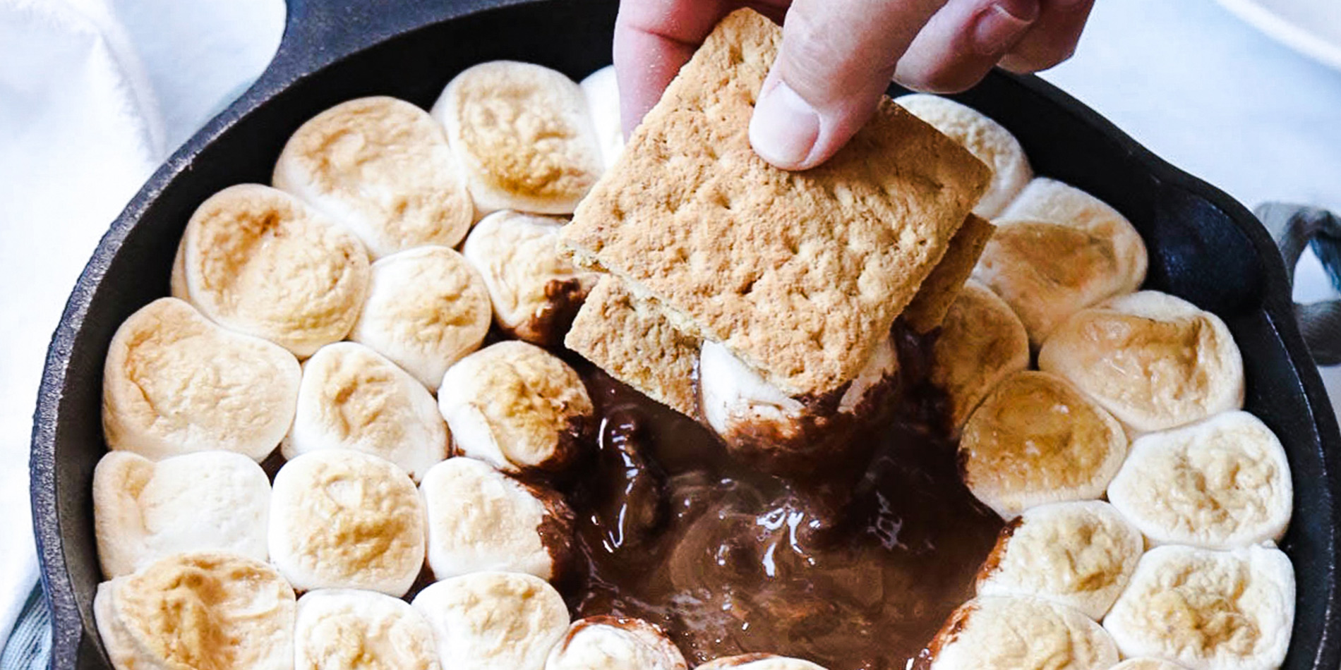 Peanut Butter Cup S'mores Dip with marshmallows and peanut butter cups in a white background