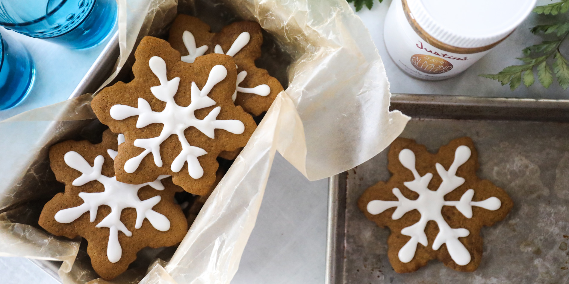 Almond Butter Gingerbread Cookies in snowflake shape on parchment paper in a pan on a white background