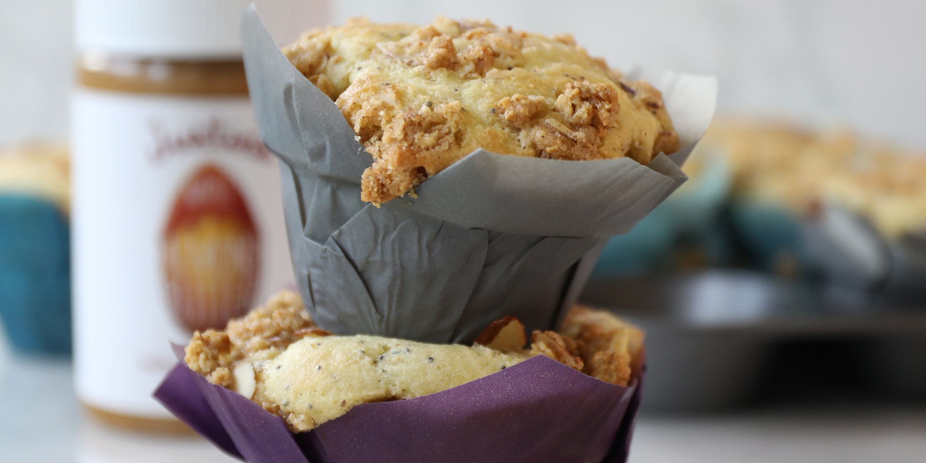 Almond Butter Poppy Seed Muffins stacked on top with almond flakes on the white background