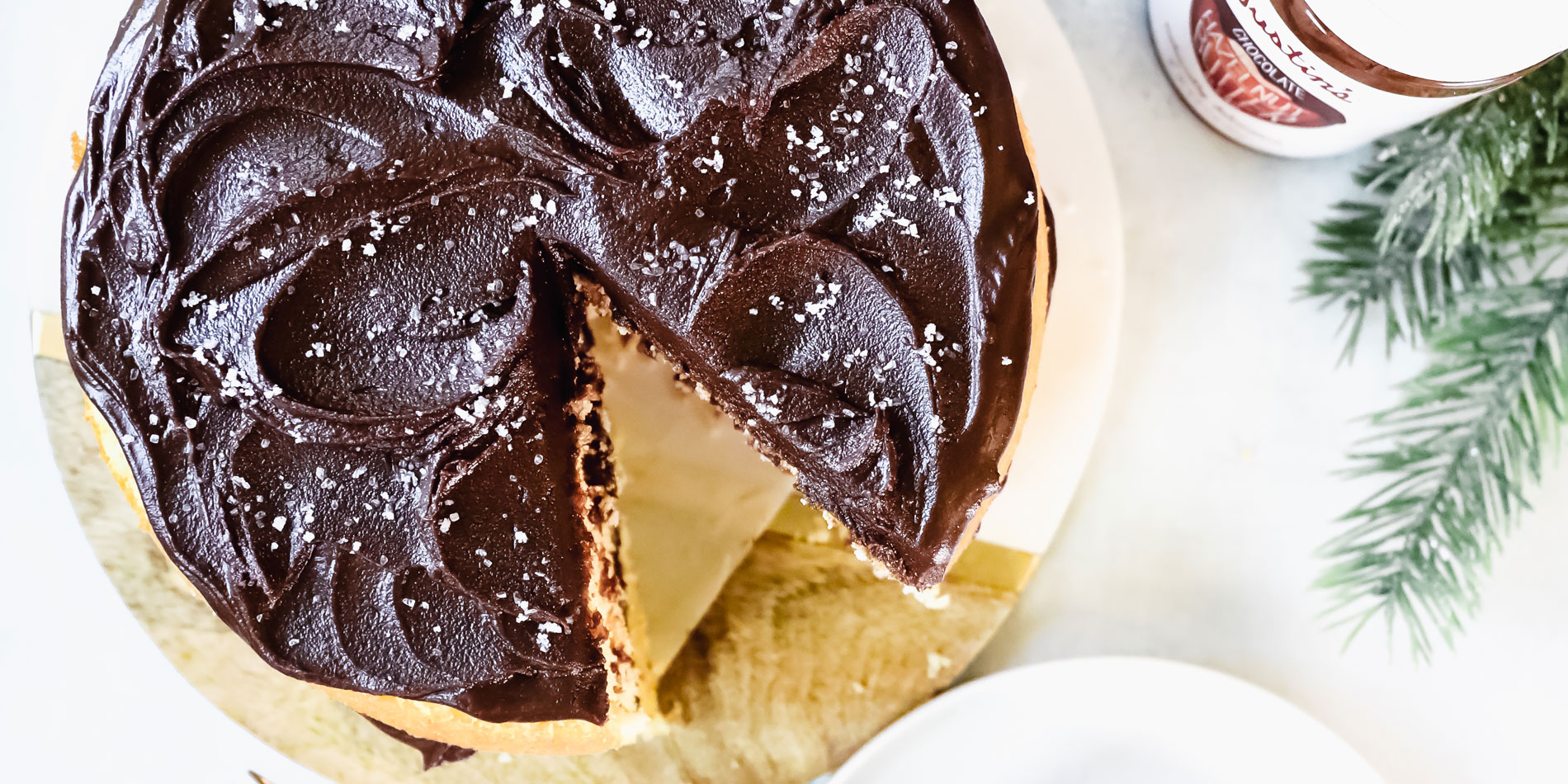 Chocolate Hazelnut Ganache with one sliced out on separate white dish with a pine tree in white background