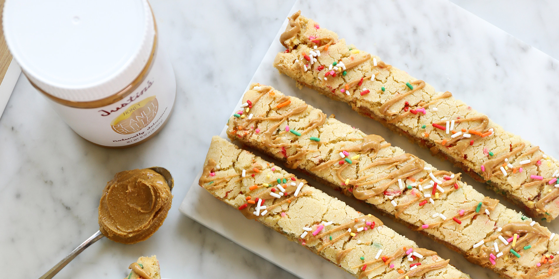 Gluten-Free Peanut Butter Biscotti on a white plate and marble tray with coffee on a white marble background