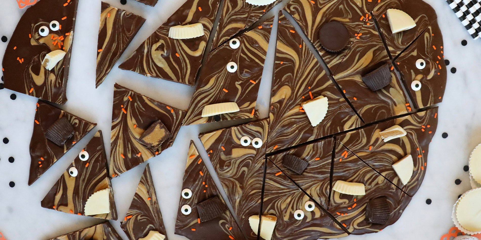 Spooky Peanut Butter Chocolate Bark cut into random pieces with googly eyes on some with flower paper and confetti decoration