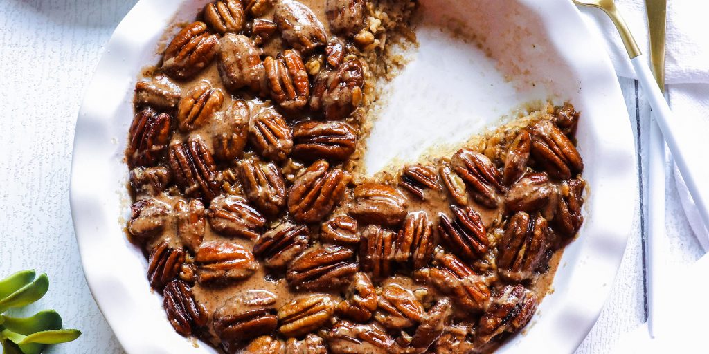 Pecan Pie Baked Oatmeal with Cinnamon Almond Butter in a white bowl with a slice cut out on separate dish on white background