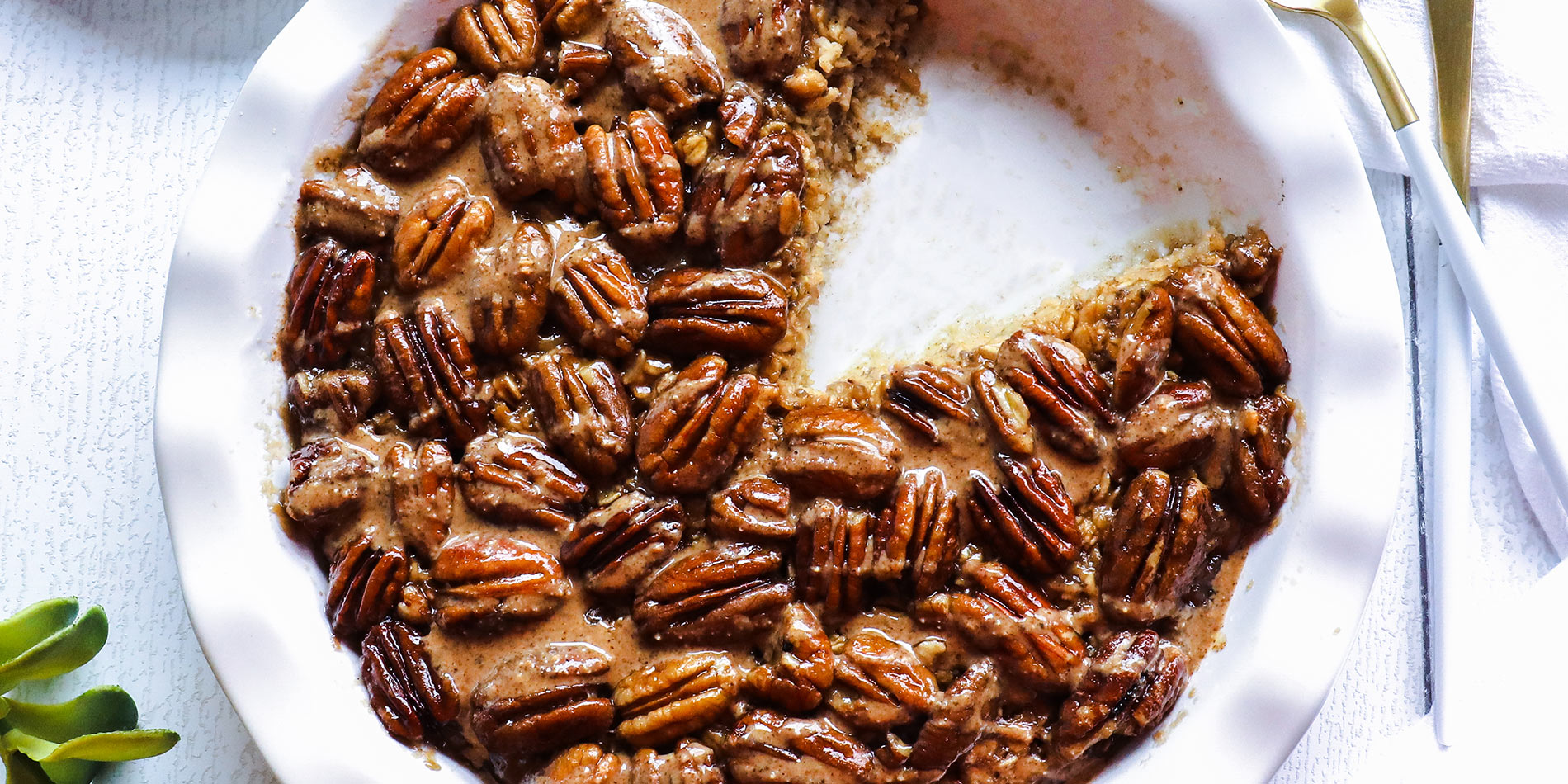 Pecan Pie Baked Oatmeal with Cinnamon Almond Butter in a white bowl with a slice cut out on separate dish on white background