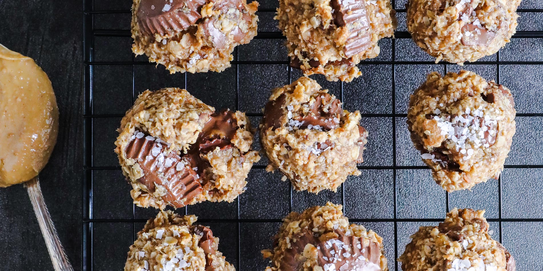 4-Ingredient Peanut Butter Banana Oatmeal Cookies on a black cooling tray with a spoon on a grainy textured background