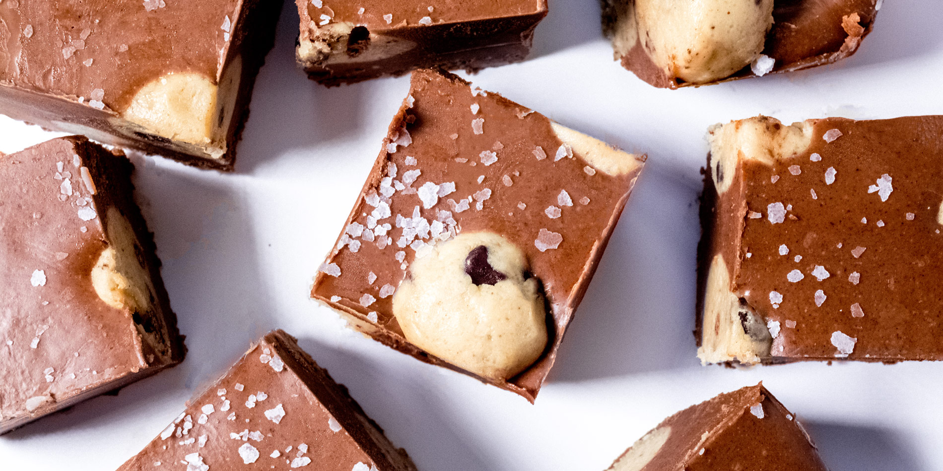 Chocolate Hazelnut Cookie Dough Fudge closeup shot of 8 slices with sea salt sprinkles on a white background