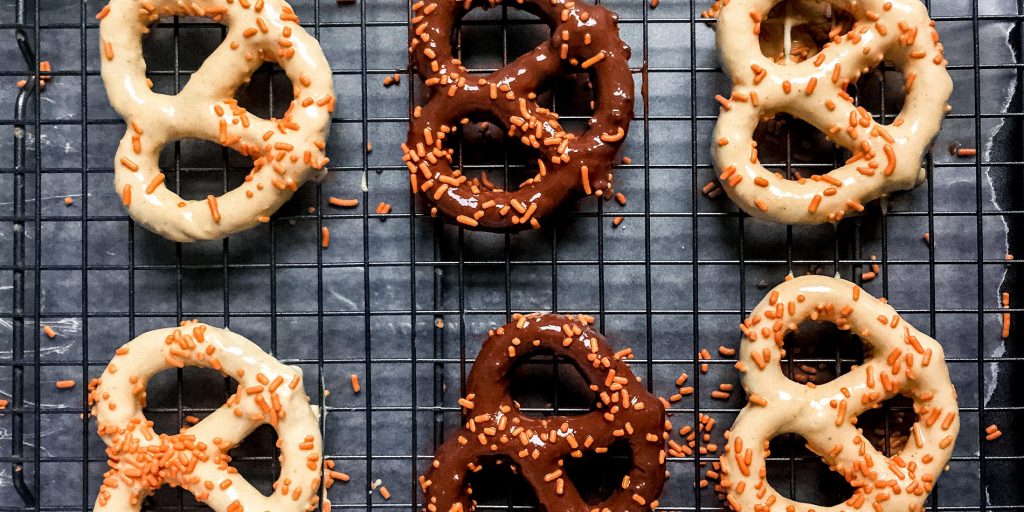 Nut Butter Cup Dipped Pretzels on a black cooling tray on white parchment on a black tray on a white background