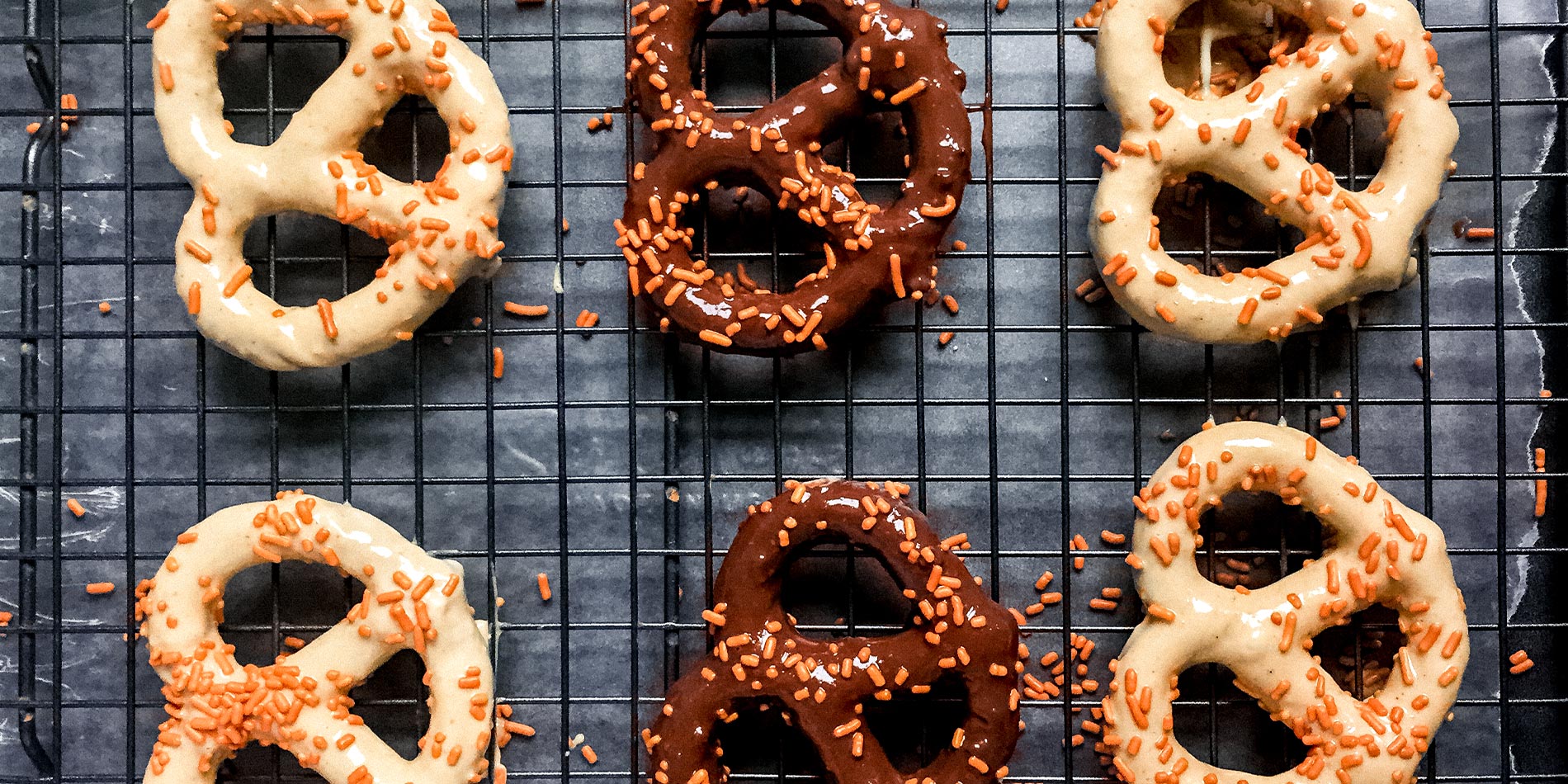 Nut Butter Cup Dipped Pretzels on a black cooling tray on white parchment on a black tray on a white background