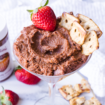 Chocolate Hazelnut and Almond Dessert Hummus on a clear glass with strawberries in the background (thumbnail image)