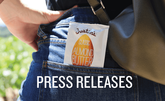 Justin's Classic Almond Butter Spread Squeeze Pack in the back pocket of jeans with "Press Releases" in white font