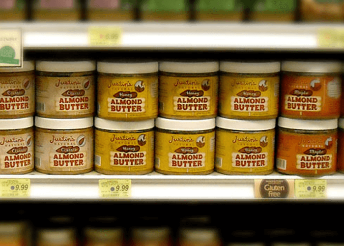 Justin's nut butter jars (16 oz) with its earlier package design stacked in the shelves of a grocery store