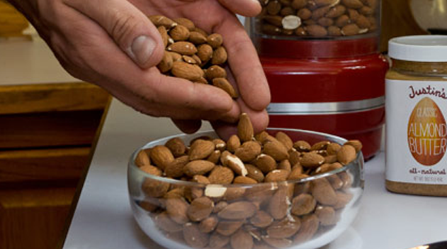 Hand pouring almonds into a round clear bowl