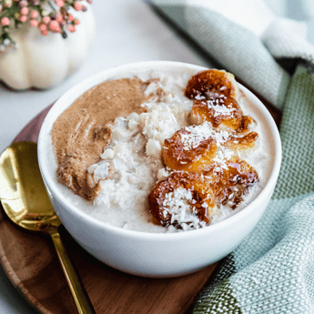 Grain Free Coconut Cauliflower Oats with Caramelized Bananas on a wood bowl with a gold spoon on a white background
