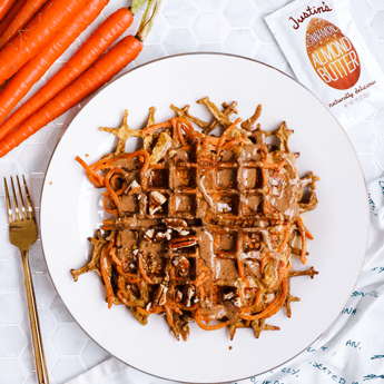 Spiralized Carrot Cake Waffle with carrots and a gold fork in the white tile background with a cloth with carrot illustration