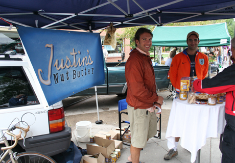 Justin under the stall at farmers market with a table display of his products