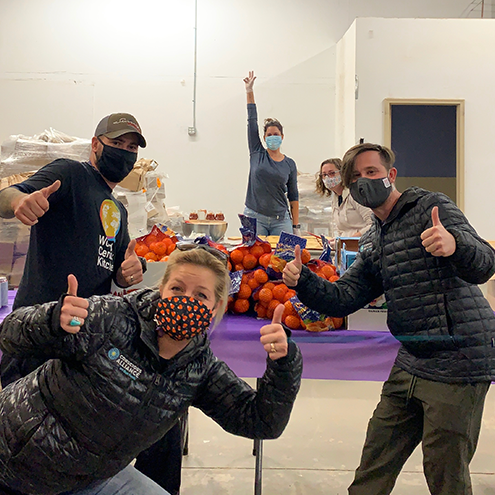 Team of people with masks on with their thumbs up, in front of a table with clementine bundles