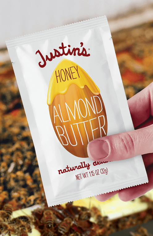 Hand holding Justin's Honey Almond Butter Spread Squeeze Pack 1.15 oz