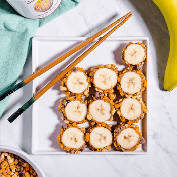 Crunchy Banana Roll on a white, rectangular plate with wooden chopsticks on top with a banana on the top right corner thumbnail image.