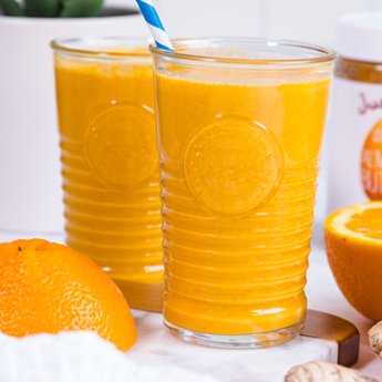 Orange Creamsicle Smoothie in tall glass cups with a white and blue straw with oranges in the background (thumbnail image)