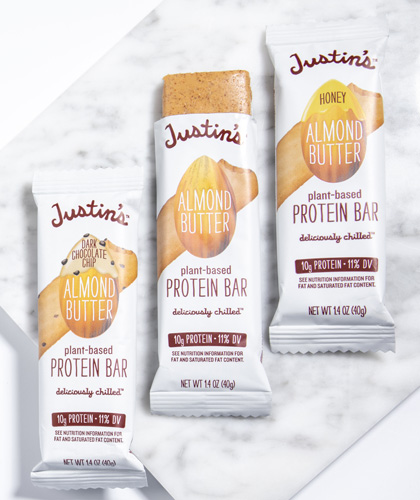 Justin's Almond Butter Protein Bars (Honey, Classic, Dark Chocolate) lined up on the right side of a marble background