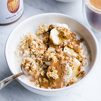 Ceramic bowl filled with Cinnamon Almond Butter Overnight Oats and milk on a marble countertop (thumbnail)