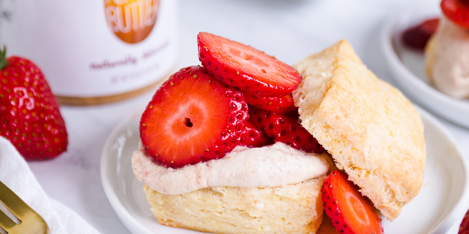 Strawberry Shortcakes stacked atop each other, topped with Dairy-Free Coconut Cream and on a small ceramic plate